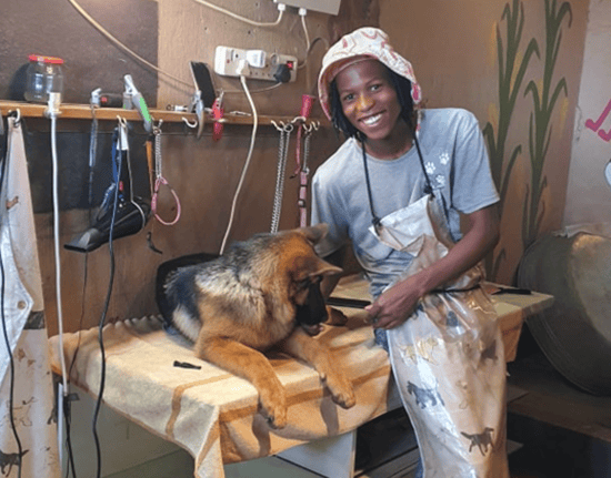 a dog groomer smiling with a german shepherd at paws at play