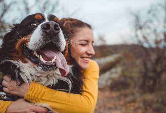 A woman hugging her dog outside