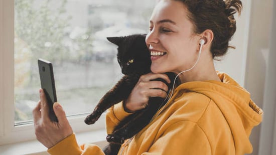 A woman holds a cat while looking at a phone