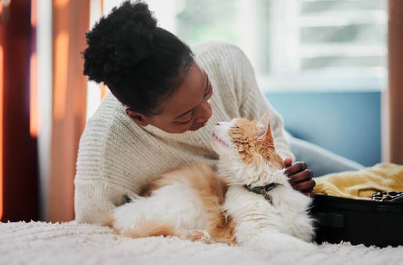 A woman petting her cat while laying on a bed