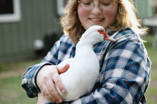 pet caretaker smiling while holding white duck