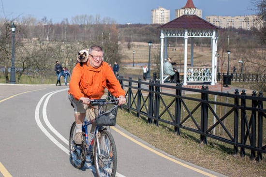 bicyclist riding with cat on his shoulder