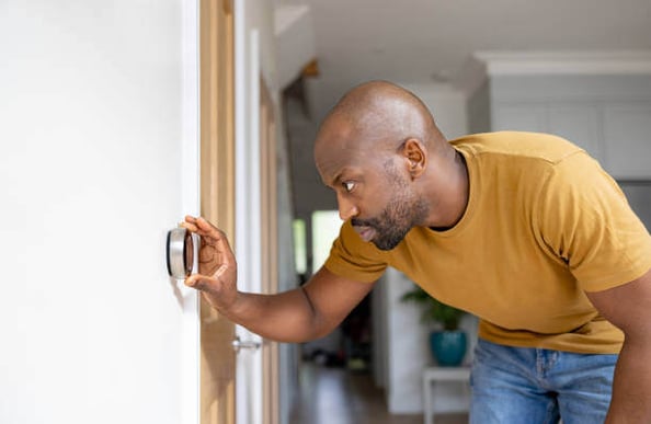 A man checks a smart thermostat