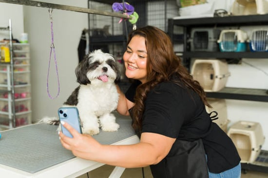 groomer taking a photo with a dog client to send to pet parent