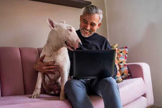 man on laptop with dog smiling