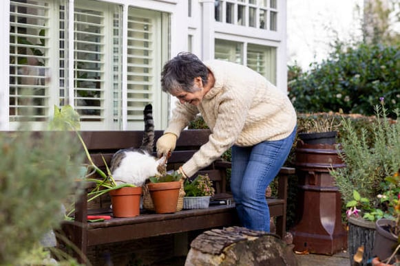 A woman gardens with her cat outside