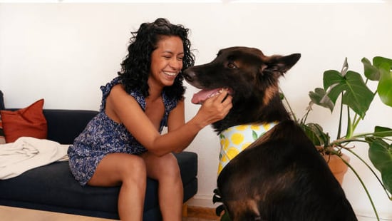 woman smiling with plant and dog in recycled bandana 