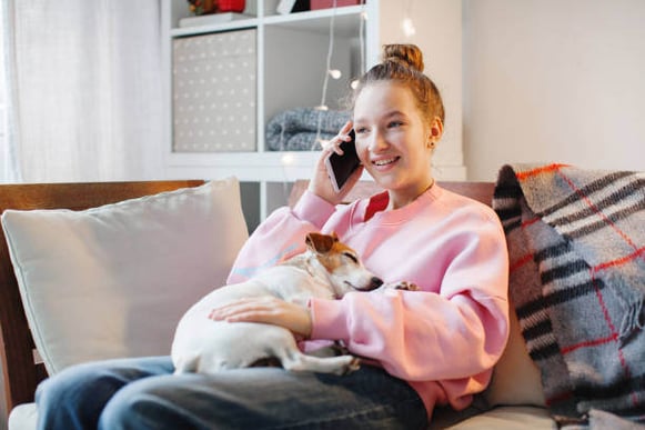 A woman talks on the phone while holding her dog