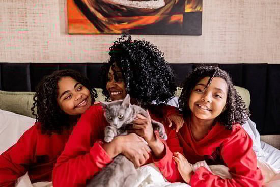 mom and children in holiday sweaters snuggling pet cat